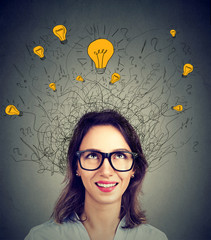 Young woman in glasses with many ideas light bulbs above head looking up