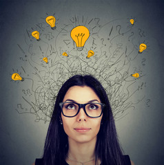 Serious woman in glasses with many ideas light bulbs above head looking up