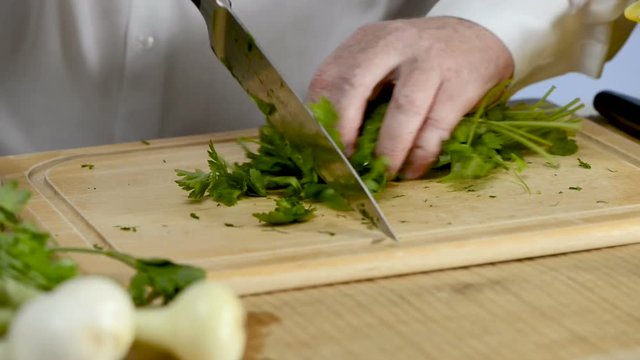 Hands of the cook knife big kitchen a fresh green parsley on a chopping board from a tree