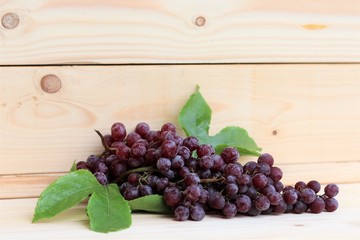 Grapes fresh fruit with leaves on wood background