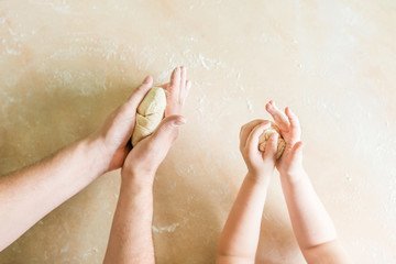 Children's and dad's hands makes raw dough