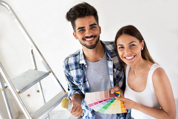 Young happy couple choosing colors for painting their home