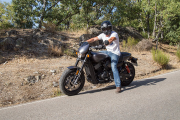 Fototapeta na wymiar Side view of man sitting on parked custom motorcycle on road in mountains. 