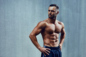Portrait of an athletic man standing shirtless and looking away with hands on his hips