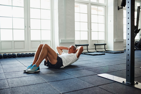 Senior man doing sit ups on a gym floor