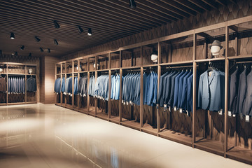 Interior of the business suit shop. Strict premium expensive suits hang in a row on hangers in...