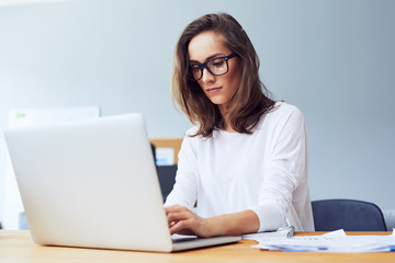 Potrait of very concetrated young startup businesswoman working hard on laptop in bright home office