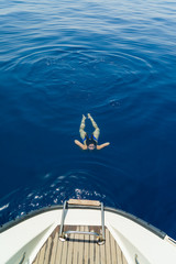 Fototapeta premium Young woman swimming by the sailing boat