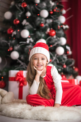 Portrait of a cute little girl on a christmas tree background.