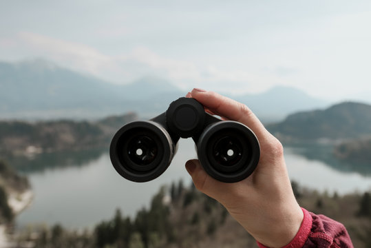 Frau blickt mit Fernglas auf den See Bled und die Alpen in Slowenien