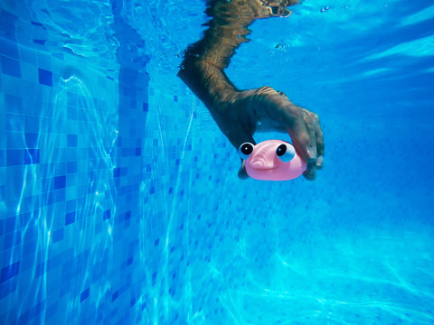 Man playing with generic rubber fish toy in swimming pool