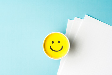 Happy emoticon/face and copy space on blue background and white papers