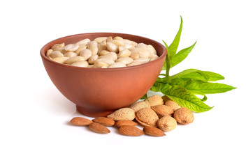 Blanched almonds In a bowl with unshelled nuts. On white background.