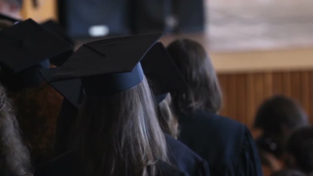 Happy graduation day, students in mantles and caps waiting for diplomas