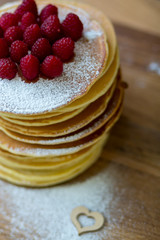 Tasty homemade pancakes with cream and raspberry. On wooden table. Village kitchen