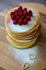 Tasty homemade pancakes with cream and raspberry. On wooden table. Village kitchen