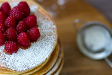 Tasty homemade pancakes with cream and raspberry. On wooden table. Village kitchen