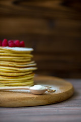 Tasty homemade pancakes with cream and raspberry. On wooden table. Village kitchen