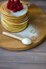 Tasty homemade pancakes with cream and raspberry. On wooden table. Village kitchen