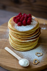 Tasty homemade pancakes with cream and raspberry. On wooden table. Village kitchen