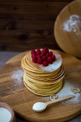 Tasty homemade pancakes with cream and raspberry. On wooden table. Village kitchen