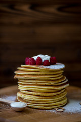 Tasty homemade pancakes with cream and raspberry. On wooden table. Village kitchen