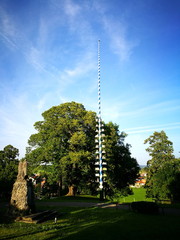 Maibaum im Licht der untergehenden Sonne vor blauem Himmel in Hirschberg bei Steingaden im...