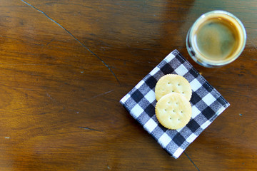 top view of espresso coffee with two pieces of cookies on piece of cloths on the wooden table with copy space for text.