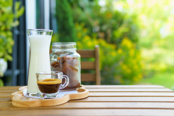 iced coffee cube latte with milk and shot of espresso on the wooden table in the garden. bright tone. with copy space for text