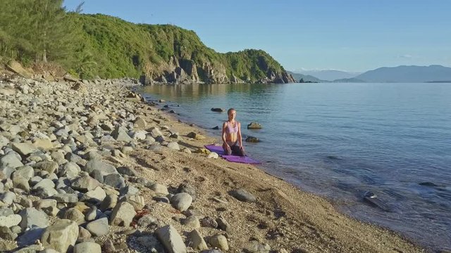 Camera Removes from Girl in Yoga against Green Hills by Sea