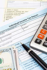 Tax form with calculator, pen, and dollar banknote; document are mock-up