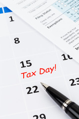 Tax day on calendar with pen, and tax form