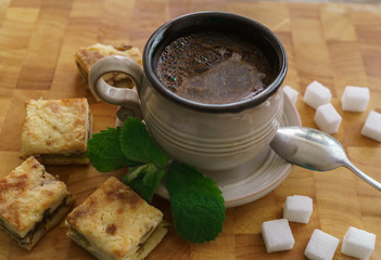A cup of fresh coffee with pieces of cake.