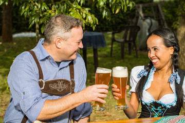 Oktoberfest - Couple in traditional bavarian clothes is drinking beer in the garden