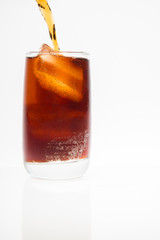 soft drink with caffeine is poured into a glass with ice on the background.