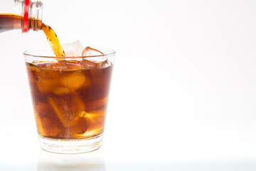soft drink with caffeine is poured into a glass with ice on the background.
