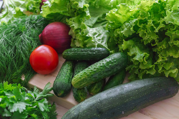 Beautiful green greens with cucumbers and red tomato and onions.