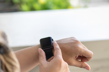 Close up of woman wearing white t-shirt and scarf using and touch her smart watch on wrist.