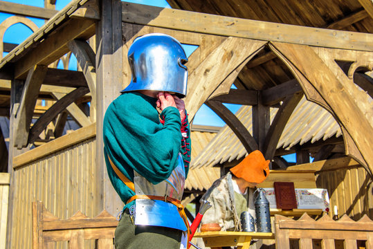 The knight wearing helmet and armor on the background of wooden castle at the international knight festival Tournament of Saint George in the Kolomenskoye museum-reserve