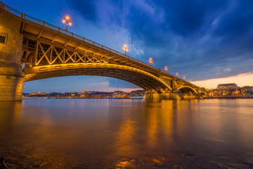 Fototapeta na wymiar Budapest, Hungary - A beautiful colorful sunset and clouds at the Margaret Bridge taken from Margaret Island at dusk with Szechenyi Chain Bridge and Buda Castle at background