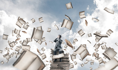 Young man sitting on books and do not want to see anything