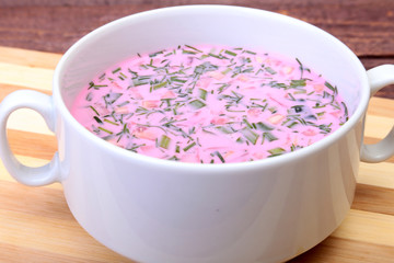 Popular spring cold soup okroshka with yoghurt. Okroshka in a bowl on wooden table. Selective focus