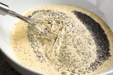 Raw dough with poppy seeds in bowl, closeup