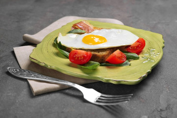 Delicious over easy egg with bread, bacon and tomatoes on kitchen table