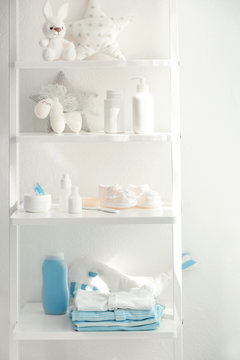 Shelves with toys and baby accessories in room