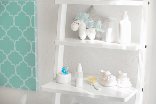Shelves with toys and baby accessories in room