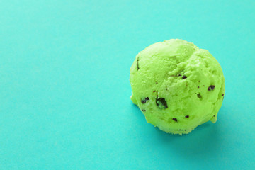 Ball of delicious mint chocolate chip ice cream on color background