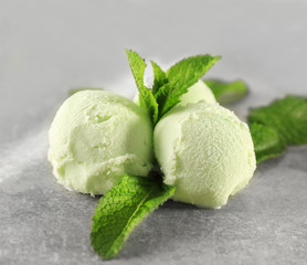 Balls of delicious mint chocolate chip ice cream and fresh leaves on light table