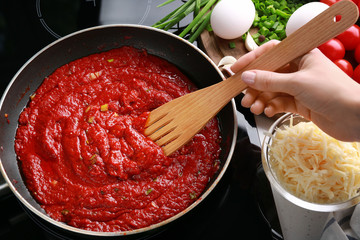 Woman cooking eggs in purgatory on stove