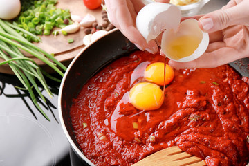 Woman cooking eggs in purgatory on stove